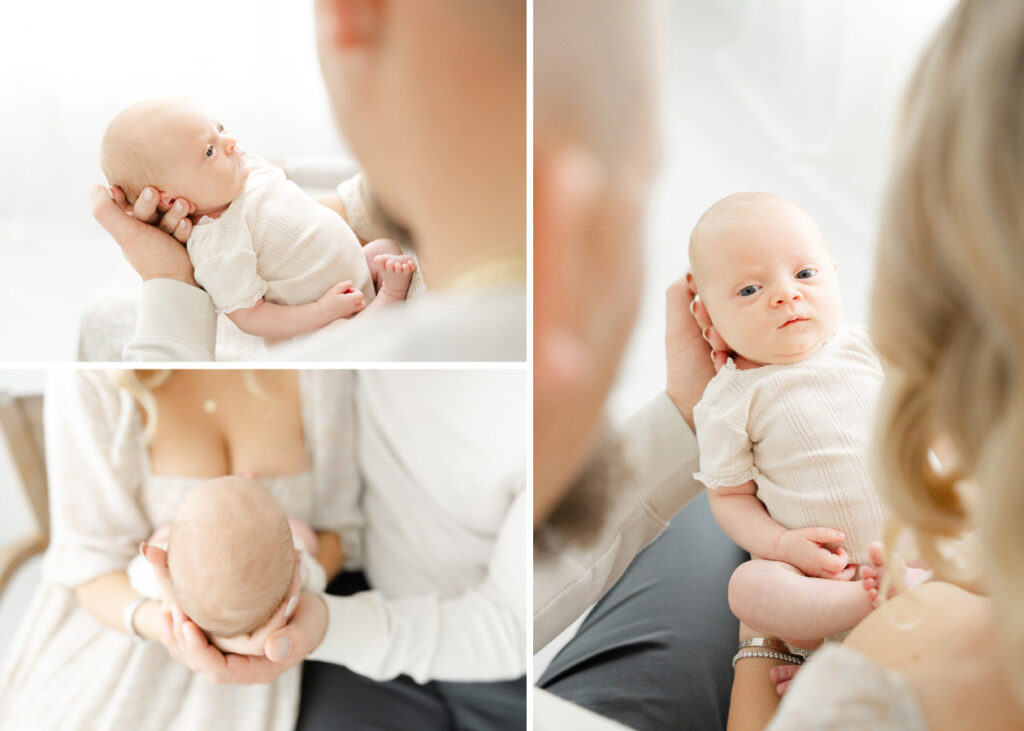 A wide awake newborn baby girl wearing a cream onesie, being held by her parents in an an all white Northern Virginia studio