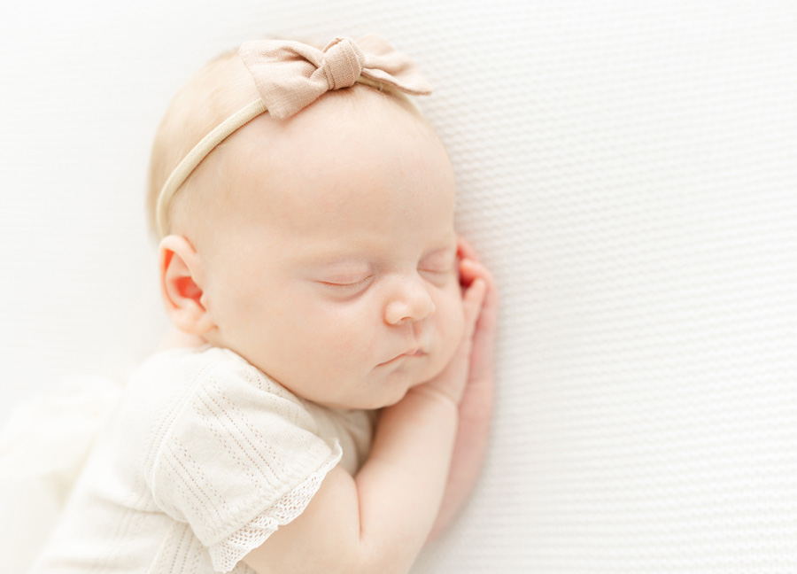 a baby girl laying on the side, resting on her hands