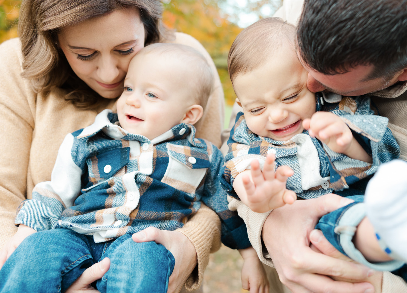 Close-up of parents cuddling and playing with their toddlers in matching plaid shirts during an outdoor session. Family Photography in Northern Virginia by Honikel Photography.