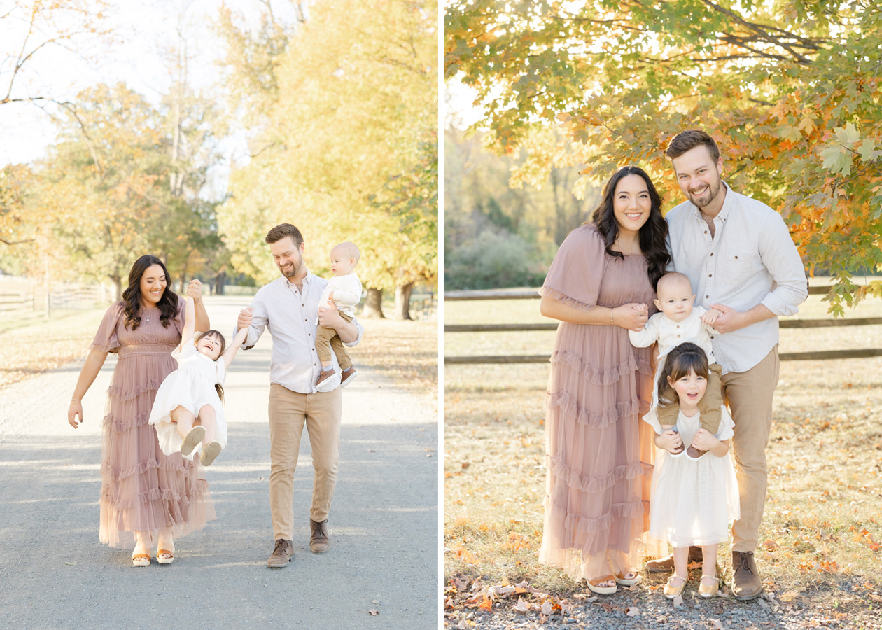 A family enjoying warm autumn family photos outdoors, with parents holding their two young children on a tree-lined path, surrounded by golden fall foliage and soft natural light.