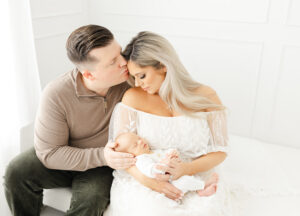 Leesburg newborn photography session featuring mom cradling baby with dad kissing moms forehead.