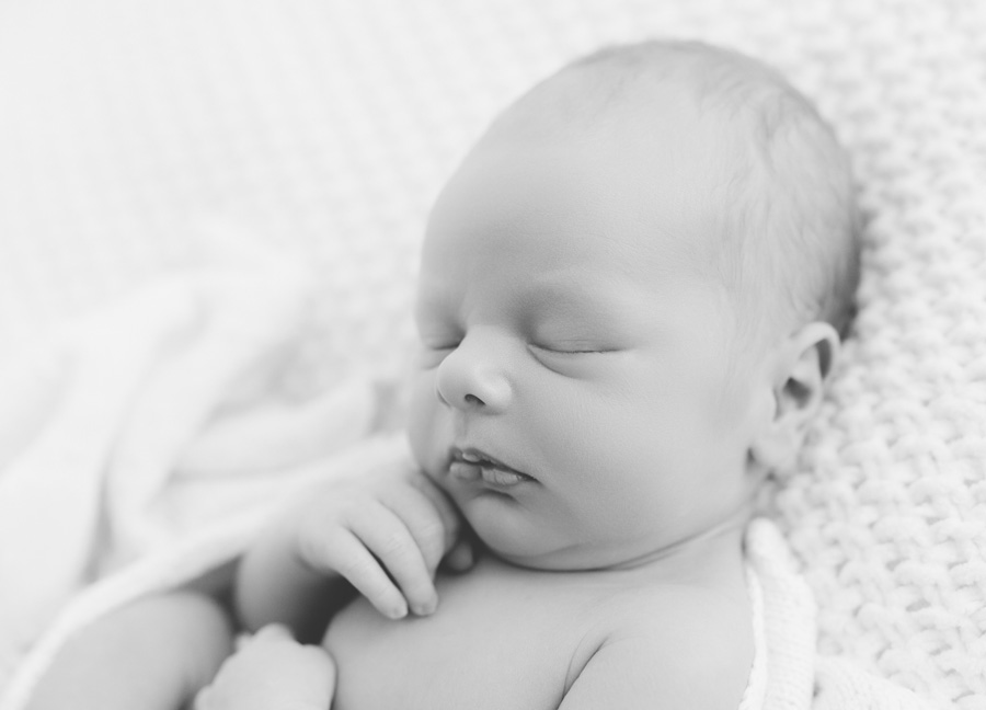 Black and white portrait of a sleeping newborn baby wrapped in a soft blanket